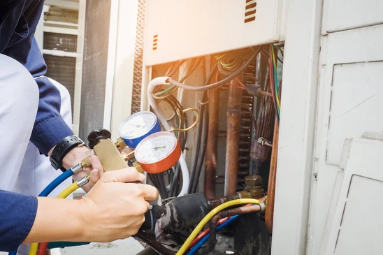 Technicien en tenue de travail bleue effectuant maintenance sur système de climatisation résidentiel
