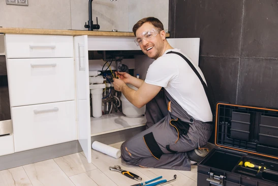 plombier Professionnel travaillant sur les conduites d'eau et les filtrers sous l'évier dans la cuisine, effectuant l'entretien et l'installation
